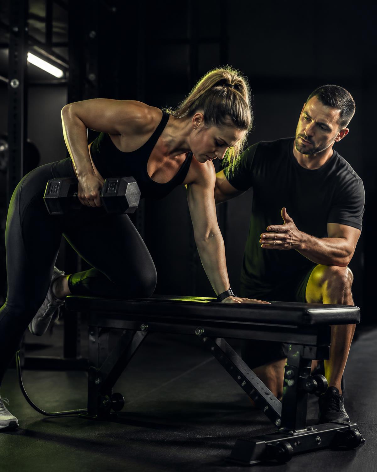 Personal trainer orientando exercício com halteres